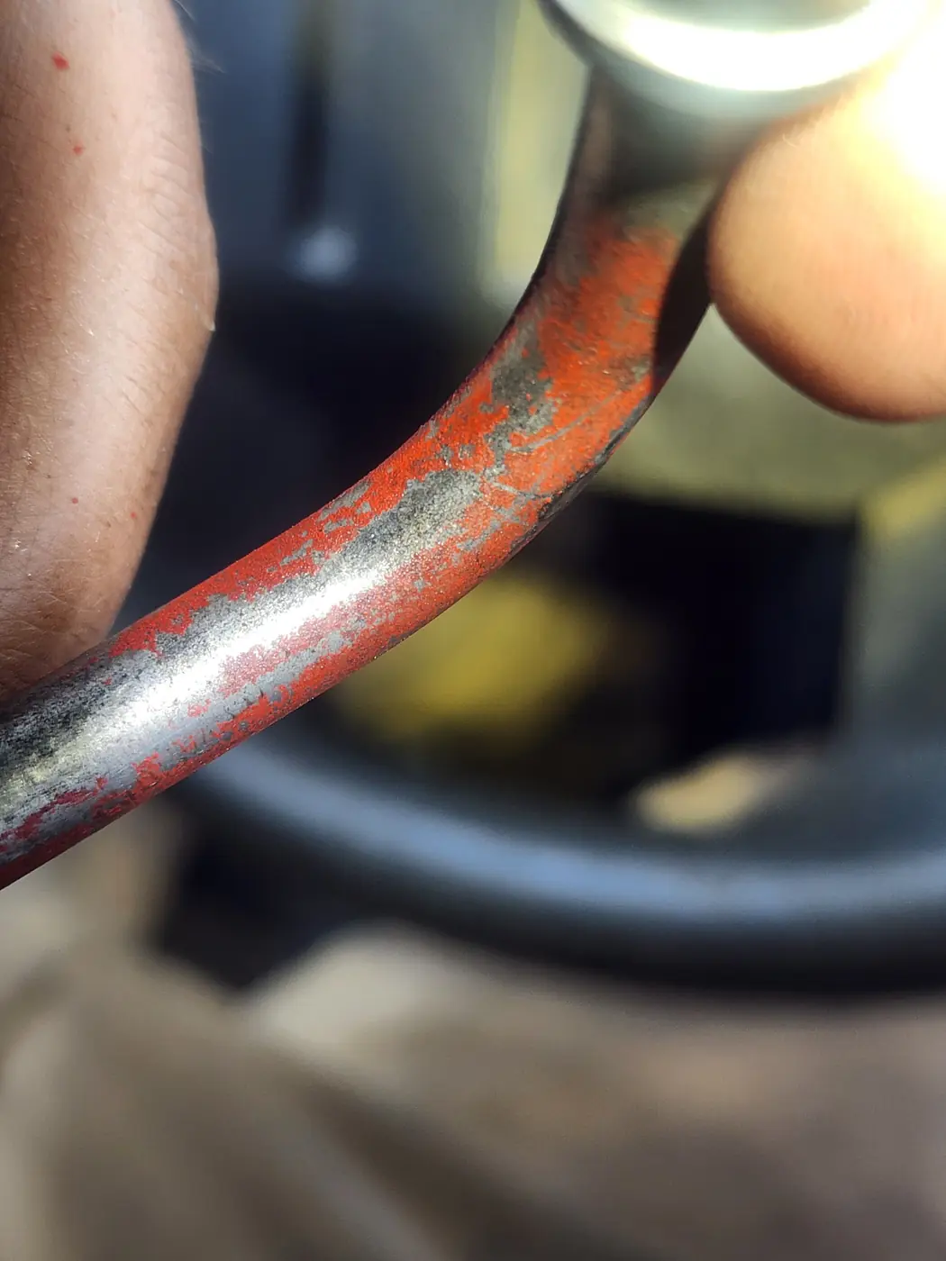 Close view of a red-painted metal tube held between fingers