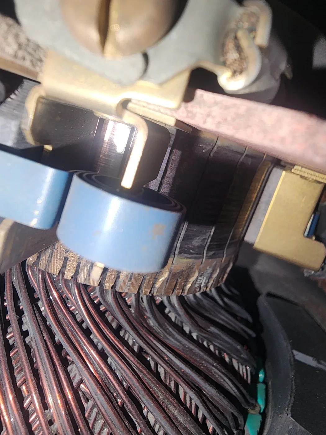 Brush holders and blue brush springs on the commutator of the hydraulic pump motor, above its copper armature windings