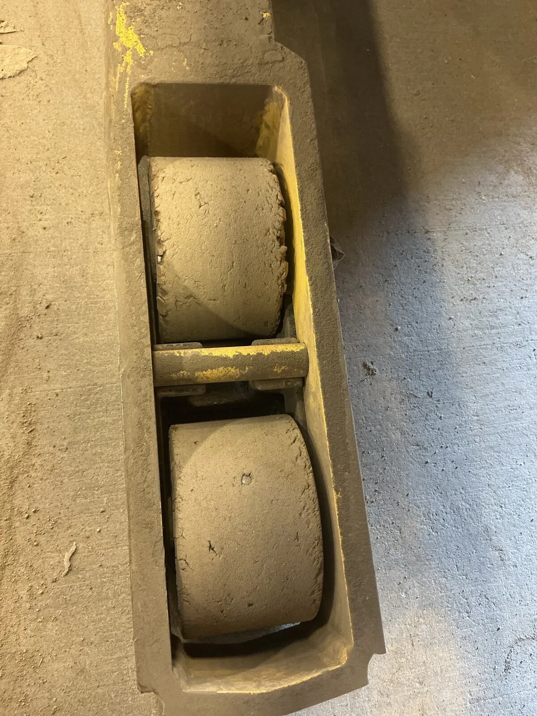 Two deteriorated load wheels mounted in a yellow reach-truck assembly