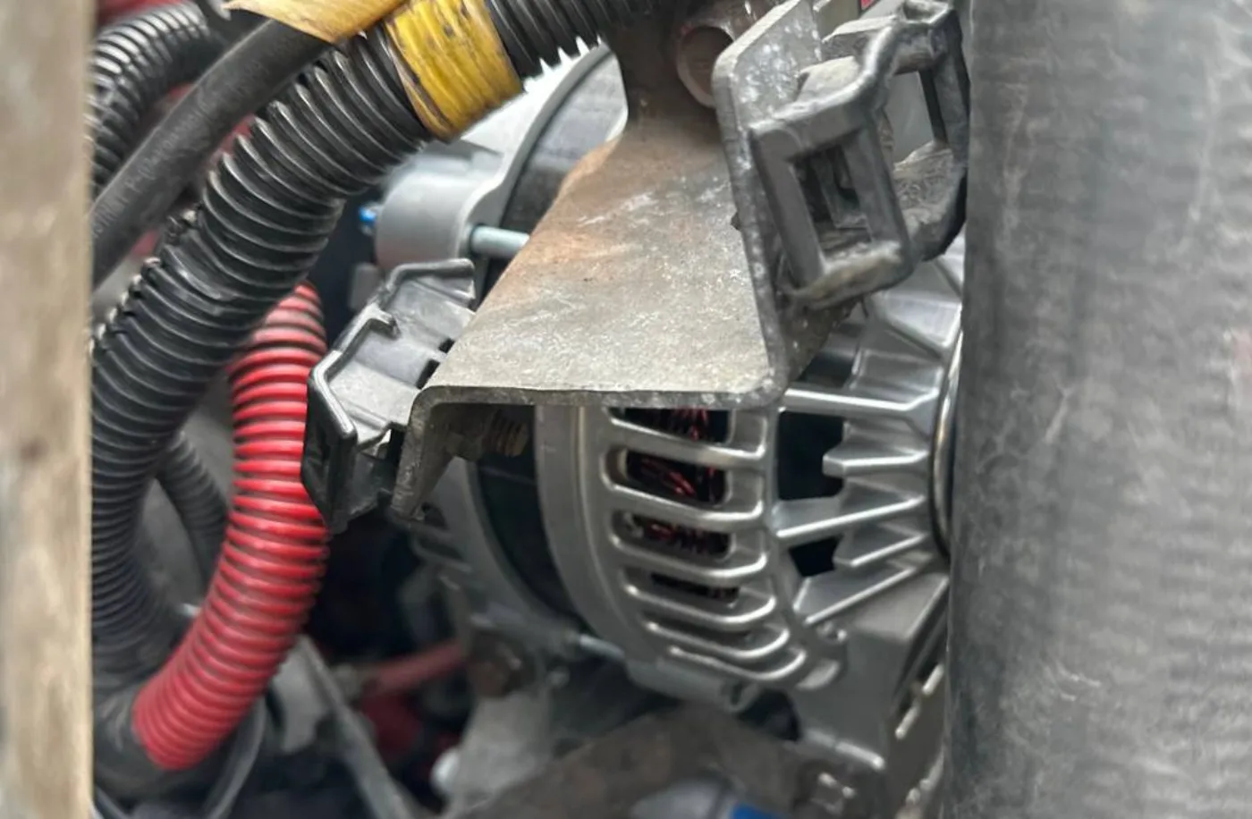 Replacement alternator installed beside the hoses and wiring on the International 4300