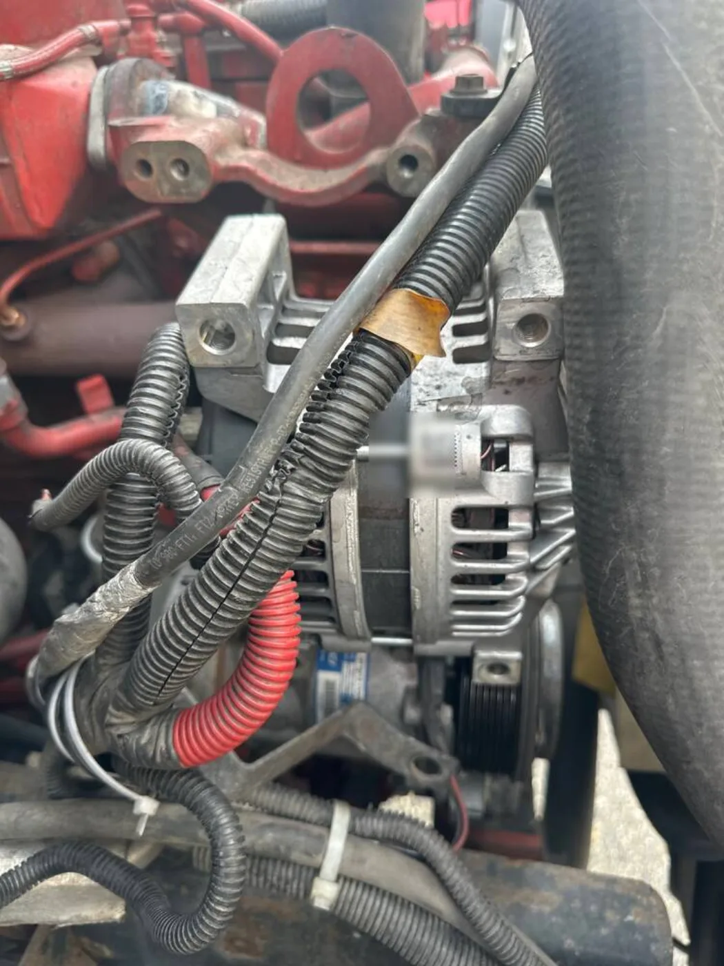 Original alternator and surrounding hoses and wiring on the International 4300