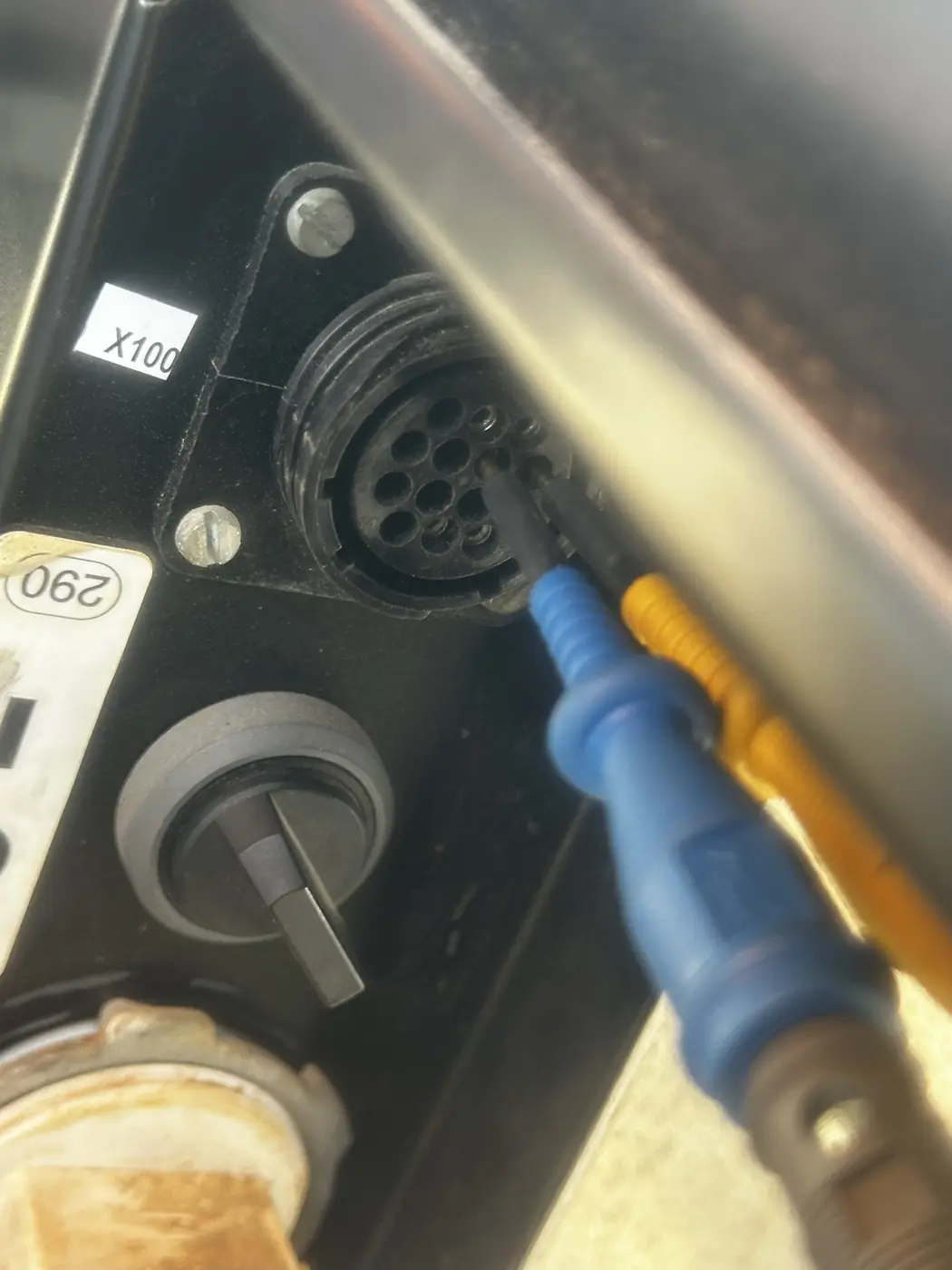 A multi-pin diagnostic connector on the machine with a test lead on one of the pins