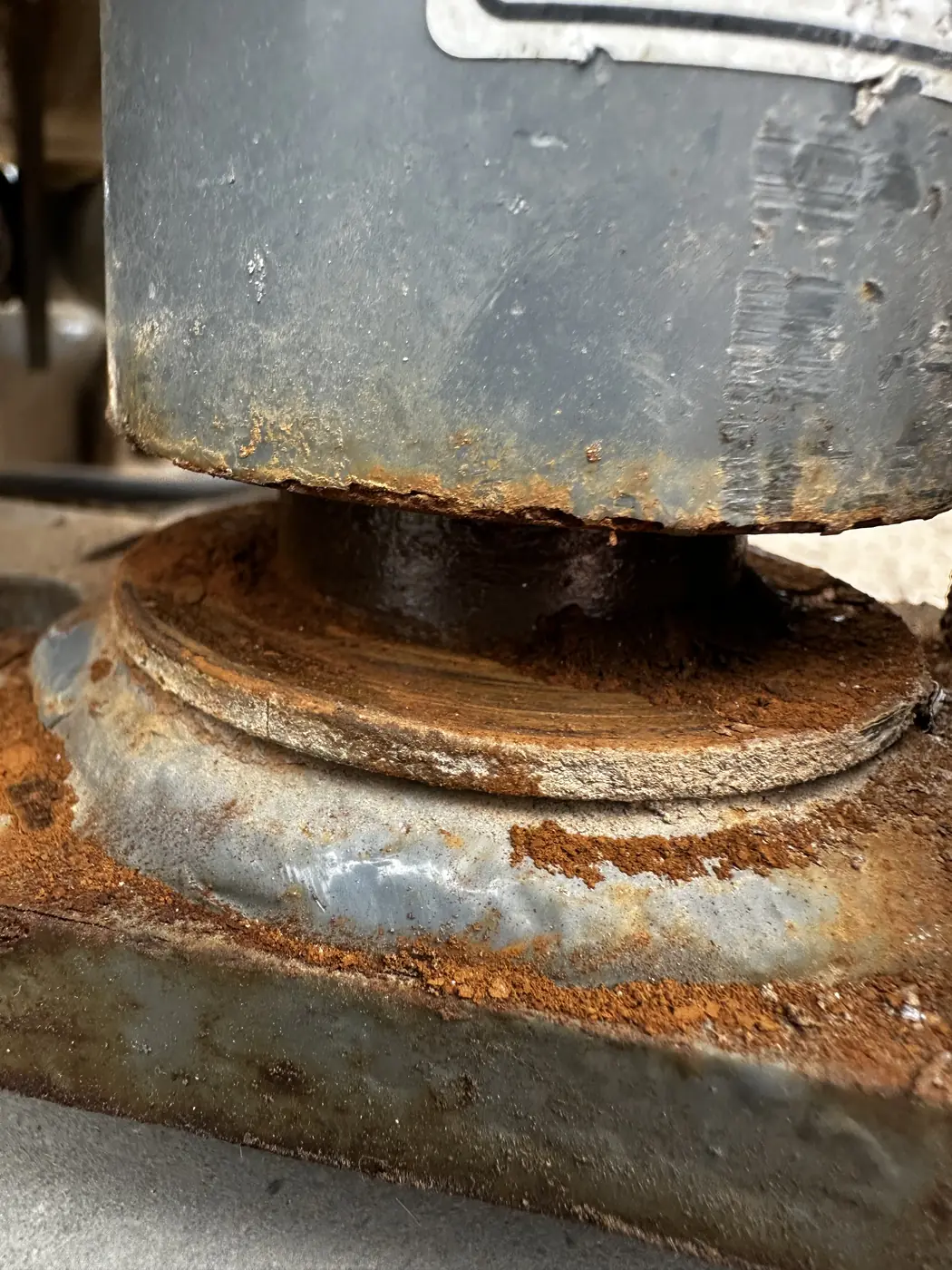 Close view of a steering pivot on the scissor lift covered in heavy rust and corrosion