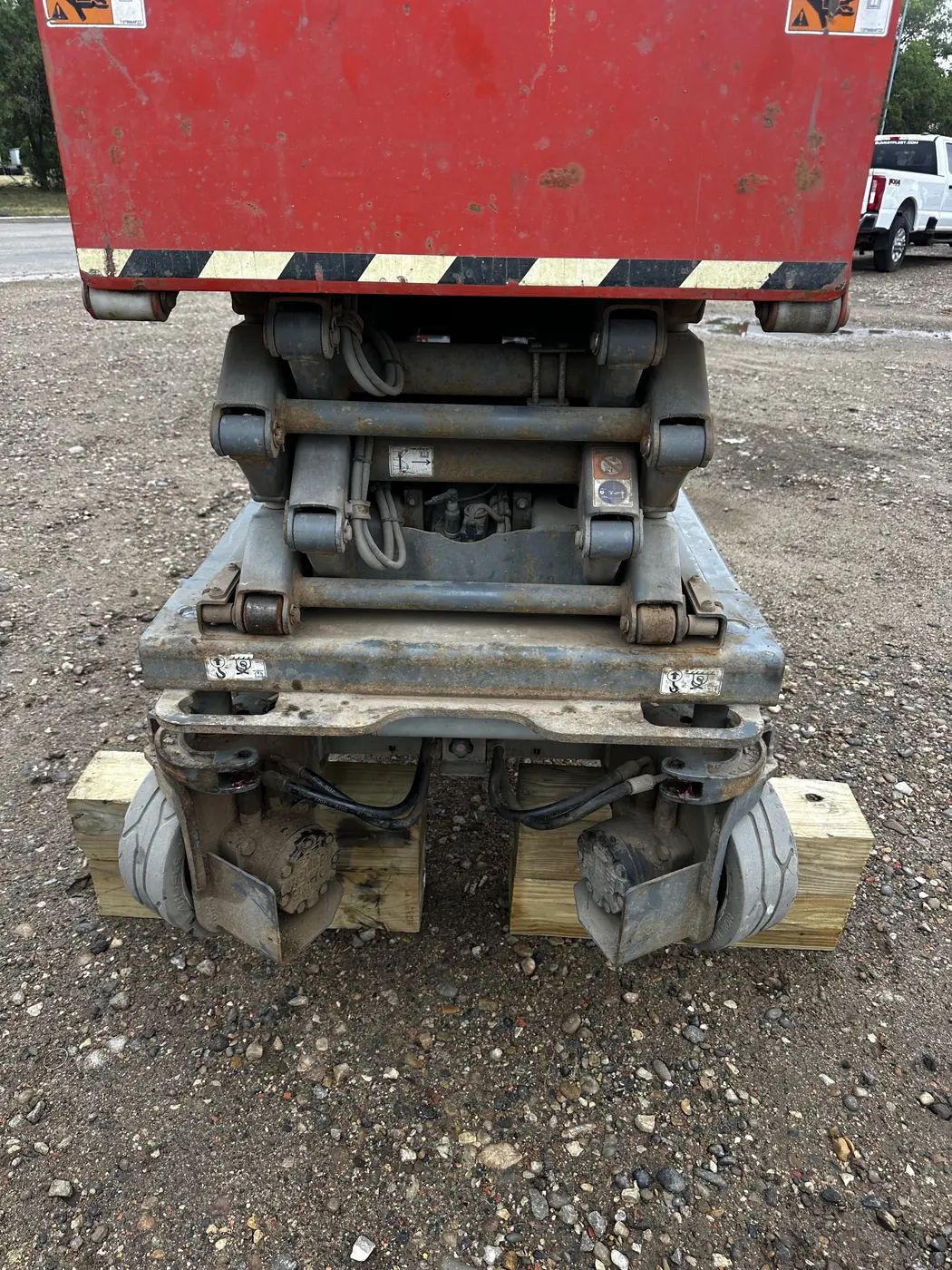 A Skyjack SJ3219 electric scissor lift parked on gravel with the platform lowered and timbers under the wheels