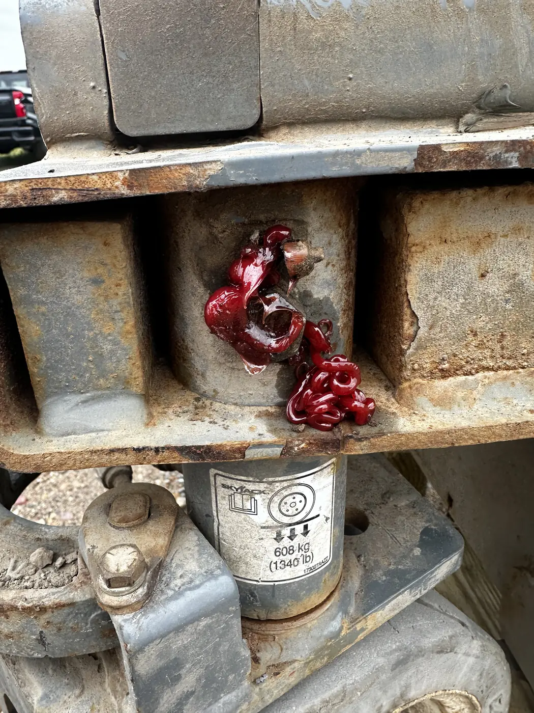 Red grease forced out around a steering pivot joint on the scissor lift frame