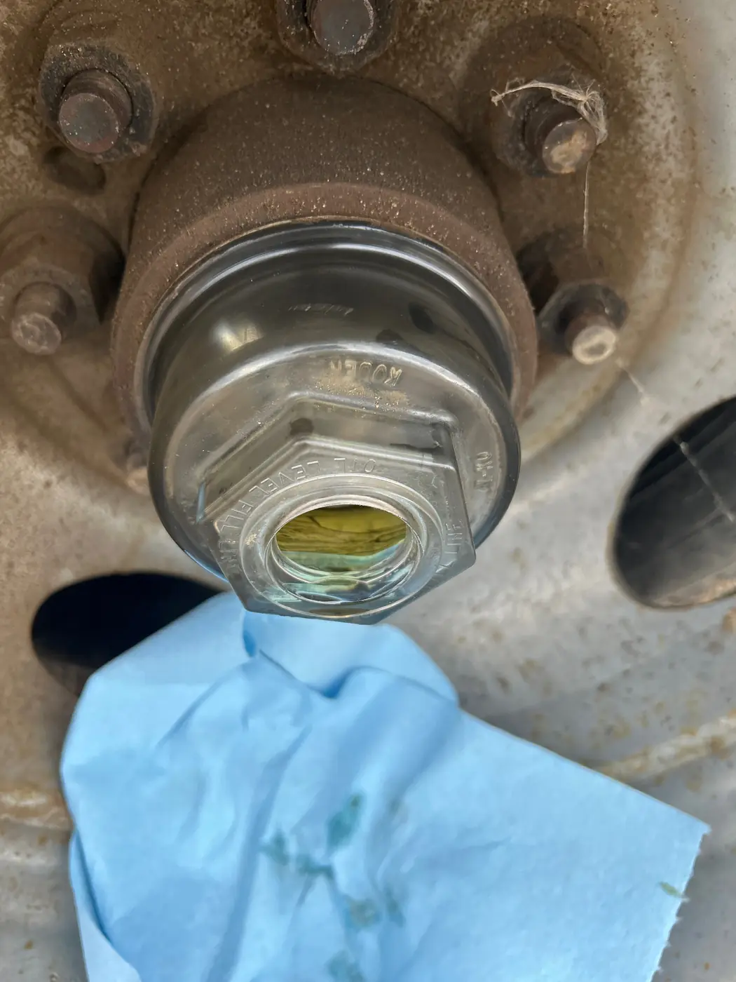 Trailer wheel hub with the clear hub cap in place and its center fill plug removed during lubrication service