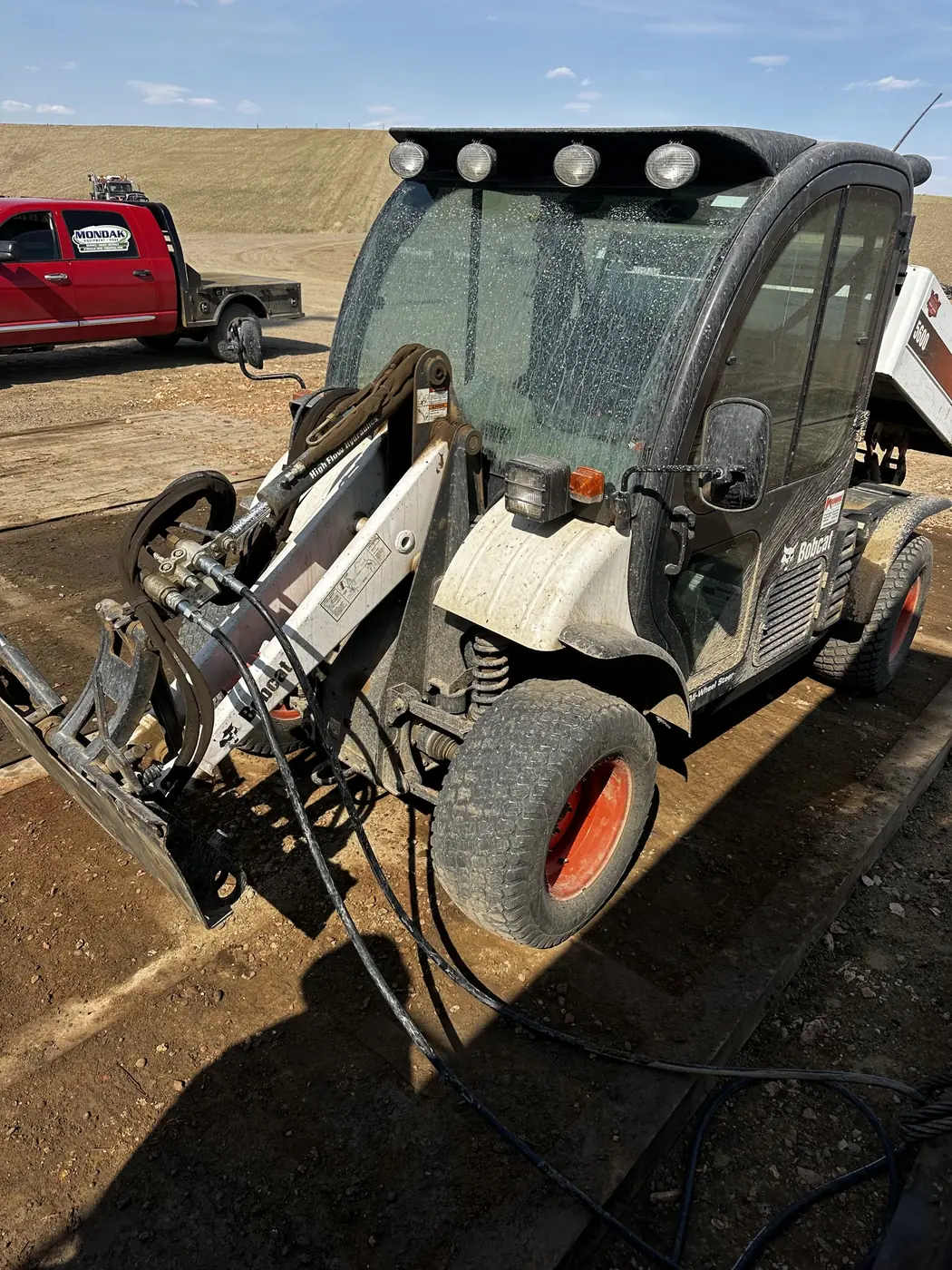Bobcat Toolcat supplying temporary auxiliary hydraulic power beside a Mondak service truck