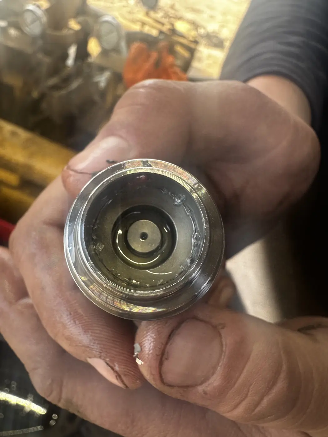 Technician showing debris inside a hydraulic fitting during diagnosis