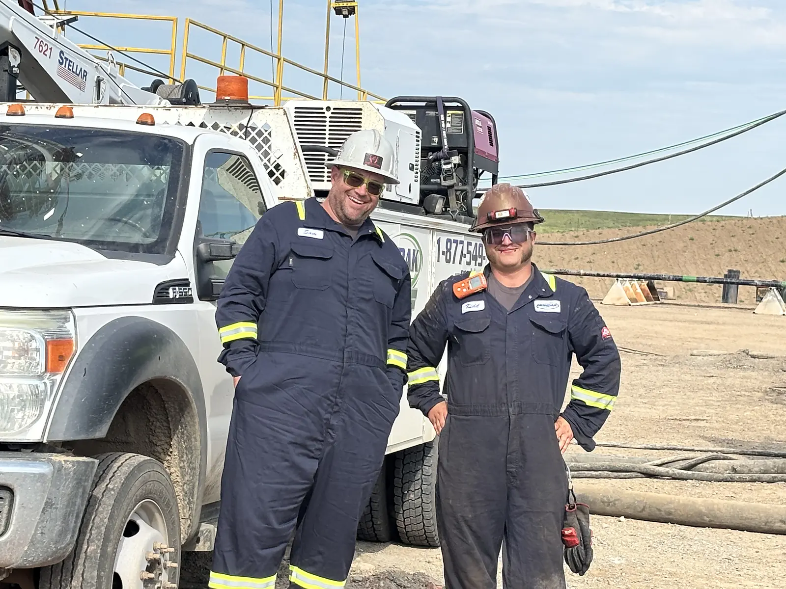 Two Mondak technicians beside a service truck at a well site