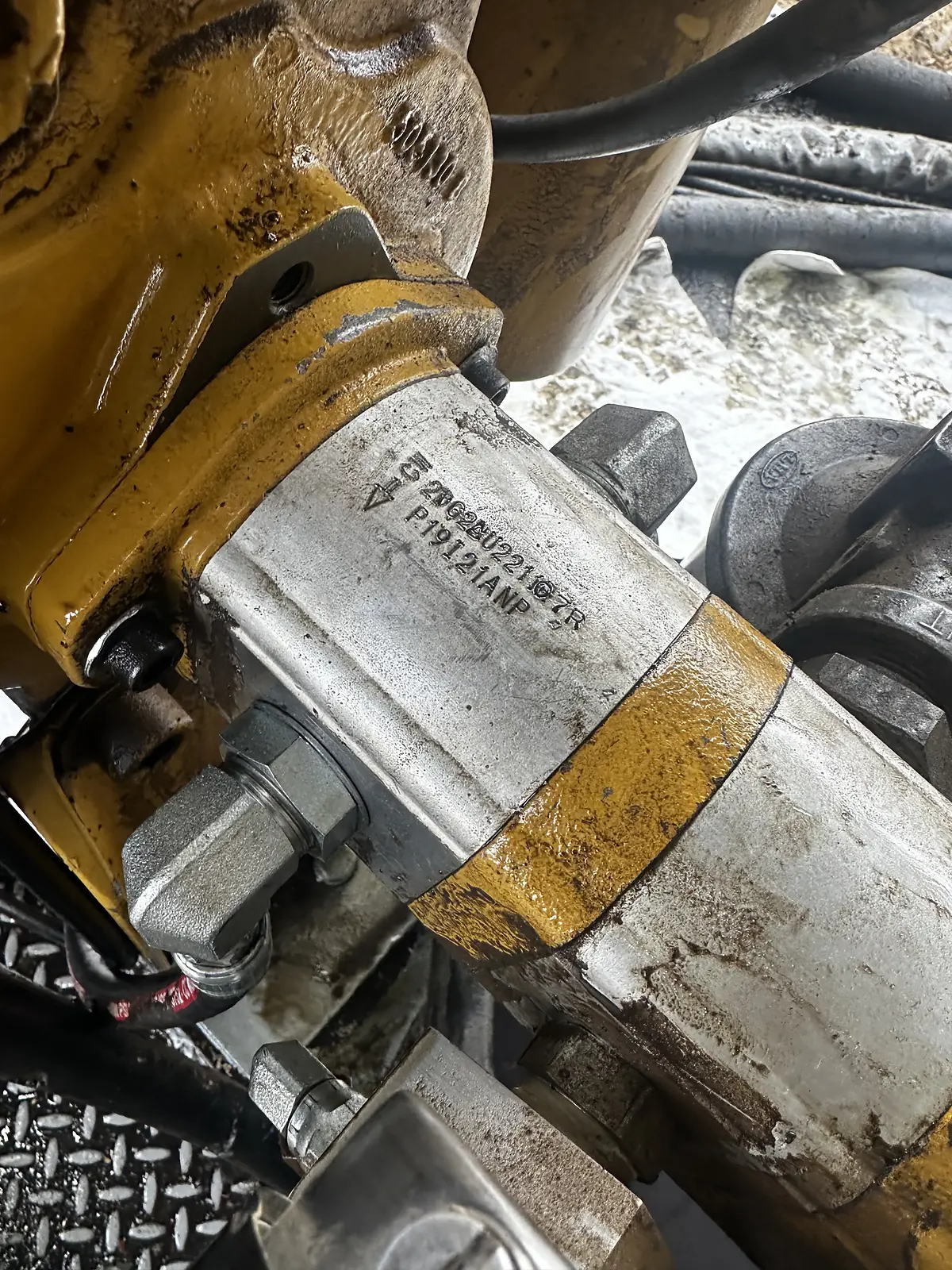 Close view of a hydraulic pump and its hose fittings on a machine